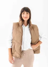 Chaleco puffer de cuello alto con cierre frontal, diseño acolchado y bolsillos laterales.