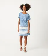 Vestido corto de jeans celeste marmolado, con cuello redondo y mangas cortas con dobladillo. Presenta tres franjas horizontales blancas en la parte inferior. Marca Marfinno.
