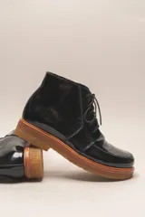 Bota acordonada de cuero vacuno con acabado charol color suela, con suela de goma tipo crepe y costuras reforzadas.