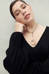 Top negro de tejido sutilmente metalizado, con escote en V y mangas abullonadas.