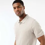 Remera polo color beige, de manga corta, con cuello y puños ribeteados en color blanco y cierre frontal de tres botones.