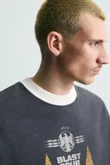 Sudadera de corte boxy fit en color gris oscuro con efecto lavado. Presenta cuello redondo en contraste color crema, manga larga con puños acanalados y estampado gráfico frontal con estrellas y tipografía estilo vintage.