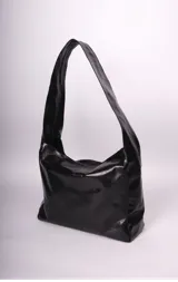 Bolso tipo hobo de cuero negro con correa ancha para el hombro.