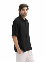 Camisa de manga corta color verde oliva, confeccionada en lino y viscosa, con cuello clásico y cierre frontal con botones. Corte suelto y estilo casual.