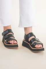 Sandalias negras de cuero con plataforma y tiras con ajuste de velcro.
