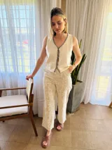 Chaleco tejido color arena con terminaciones en punto festón negro.