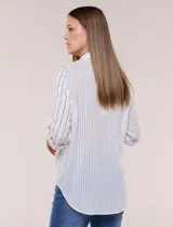 Camisa de calce holgado en género liviano con estampado a rayas verticales, cuello camisero clásico y abotonadura frontal a tono. Presenta mangas largas regulables con presilla y botón para ajustar a tres cuartos, espalda con canesú y suave pliegue central, y ruedo curvo estilo camisero.