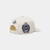 Gorra color beige con visera plana y parche bordado en el frente con escudo y la inscripción 'GOLF'.