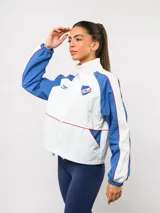 Campera deportiva Umbro del Club Nacional de Football, con diseño de bloques de color en azul marino y blanco. Presenta cuello alto, cierre frontal completo, bolsillos laterales y el escudo del club junto al logo de la marca en el pecho.