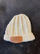 Gorro de lana tejido con diseño de trenzas y vuelta en el borde, color blanco, con etiqueta de cuero sintético con marca grabada.