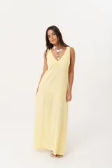 Vestido largo amarillo con escote en V y espalda con tirantes anchos. Confeccionado en lino imperial, con tajos a ambos costados y un diseño que entalla y realza la silueta.