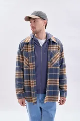Sobrecamisa a cuadros en tonos azul marino, beige y marrón, con cierre frontal de botones, bolsillos con solapa en el pecho y mangas largas.