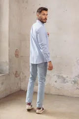 Camisa celeste a rayas verticales blancas, de corte slim fit, con cuello clásico y mangas largas.