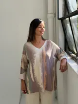 Sweater de punto con diseño abstracto en tonos tierra, verde y beige, de corte holgado, cuello en V y mangas largas con puños vueltos.