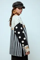 Sweater de punto con diseño geométrico y a rayas, de corte holgado y manga larga. Presenta un patrón combinado de lunares en las mangas, rombos en la parte superior y rayas verticales en el cuerpo.