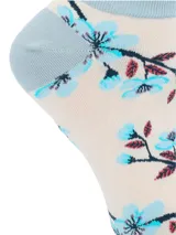 Medias cortas de algodón con diseño estampado de flores celestes sobre fondo beige y detalles en celeste en talón, puntera y borde superior con terminación ondulada.