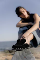 Zueco negro de cuero gamuza con plataforma forrada y tachas plateadas.