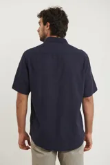 Camisa sport de manga corta, confeccionada en una mezcla de lino y algodón. Presenta cuello clásico, cierre frontal con botones de coco y un bolsillo aplicado en el pecho.