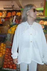 Canguro blanco de tejido waffle con capucha, cierre parcial con botones de madera y bolsillo tipo canguro.