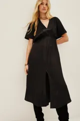 Vestido midi de color negro con escote en V, mangas cortas y cintura elástica. Presenta un diseño fluido con una abertura frontal central en la falda.