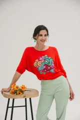 Remera roja de mangas largas con estampado abstracto de círculos y corazones en tonos celeste, verde, naranja y rosa.