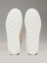 Zapatillas urbanas Calvin Klein modelo Classic Cupsole, color crema, con capellada de cuero gamuzado, interior de espuma, forro de malla de poliéster y suela de TPR. Presentan cordones, detalle de pala vega, lengüeta trasera acolchada y logo CK en el lateral.