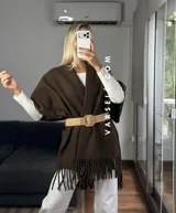 Poncho de tejido suave color blanco, con diseño abierto y flecos en el ruedo inferior.