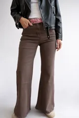 Pantalón tipo jean de corte wide leg y tiro alto, color marrón chocolate. Confeccionado en tejido elástico, cuenta con cierre frontal y bolsillos laterales.