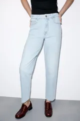 Jeans de tiro alto con corte mom fit, diseño de cinco bolsillos, cierre frontal con cremallera y botón.