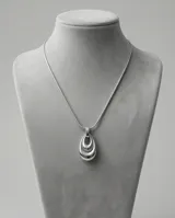 Collar de acero con cadena tipo serpiente y dije colgante en forma de lágrima con diseño de capas concéntricas.