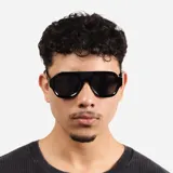 Lentes de sol con armazón de acetato negro y diseño de puente plano, estilo aviador moderno con cristales oscuros.