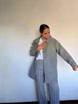 Tapado de paño gris, con cuello solapa, cierre frontal con botones y bolsillos laterales.