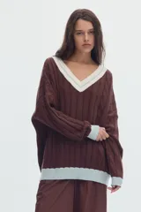 Sweater de punto oversized de color marrón, con escote en V, detalles de ochos y puños, cuello y ruedo en tono celeste y blanco.
