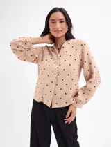 Blusa de algodón color bordó con estampado de lunares claros, cuello mao, cierre frontal con botones y mangas largas.