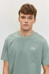 Remera verde militar de manga corta, con cuello redondo y pequeño estampado tipográfico blanco en el pecho.