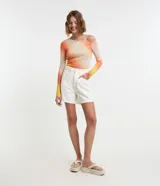 Short de sarga color blanco, corte mom, tiro alto, con trabillas en la cintura y bolsillos. Tiene cierre tradicional por botón y cremallera.