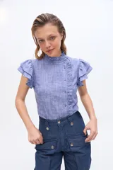 Blusa de manga corta con volados en los hombros, cuello alto con ribete fruncido y cierre frontal desplazado con botones y detalle de volado.
