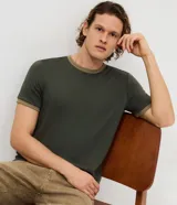 Remera de algodón color verde oliva con cuello redondo y bordes de mangas en tono beige contrastante. Diseño básico de corte cómodo y acabado liso.
