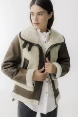 Chaqueta tipo gamulán de cuero color camel con interior y detalles en piel sintética color crema. Presenta cierre frontal, bolsillos laterales con cierre y cuello amplio con solapas.