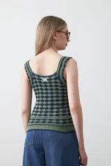 Top tejido sin mangas con diseño geométrico de rombos en relieve, en tonos azul marino y beige. Presenta escote amplio y breteles tejidos.