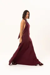 Vestido largo de color bordó, con escote halter profundo y corte a la altura de la cadera con falda amplia.