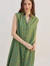 Vestido camisero midi sin mangas, de corte recto y holgado, con estampado geométrico psicodélico en tonos verdes y cuello camisero con cierre frontal de botones.