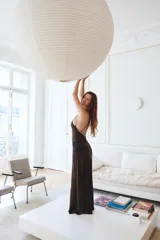 Vestido midi de corte al bies con cuello halter y tirantes finos. Presenta un diseño fluido en color marrón con aplicaciones de encaje a contraste en el frente y lateral. Cuenta con cierre lateral mediante cremallera oculta.