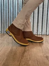 Botín marrón de cuero con elásticos laterales, suela de goma color caramelo y puntera reforzada.