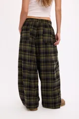 Pantalon de corte oversize y tiro medio, confeccionado en tela con estampado de cuadros en tonos marrones y negros. Presenta una silueta amplia y holgada con cintura elástica y cordón ajustable.