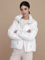 Campera puffer color blanco nacarado, con cuello alto y cierre frontal con botones a presión.