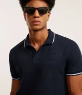 Remera polo blanca de viscosa texturizada con rayas, cuello y puños de mangas cortas en ribana con detalles contrastantes en negro.