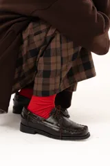 Zapato náutico de cuero color chocolate con horma cuadrada. Presenta detalles de pasamanería en cuero descarne que recorren el frente y los laterales, cordones frontales y suela plana con pequeño taco.