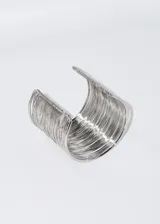 Pulsera brazalete rígido color dorado, con diseño de múltiples hilos finos.