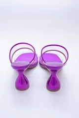 Sandalias plateadas con taco de forma geométrica y tiras transparentes.